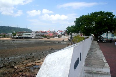 Wall along Casco Viejo with the muddy shoreline in the foreground and French and Spanish colonial buildings in the background.