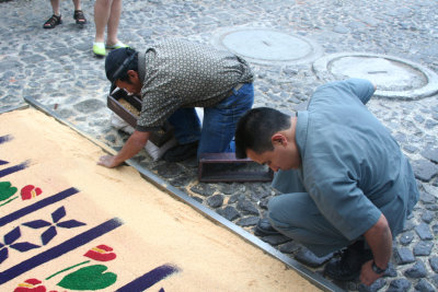 These men were using this long piece of wood to create the border of the carpet.