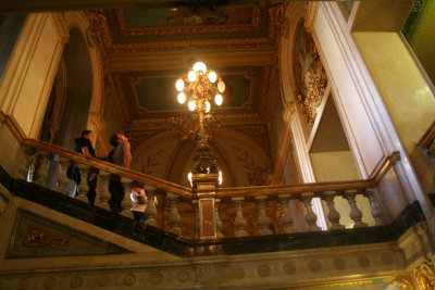 Interior shot of the National Theater with a marble staircase, a chandelier and a golden ceiling.