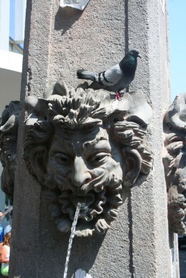 Close-up of the wonderful face on the clock tower spewing water.   A pigeon was perched on the head.