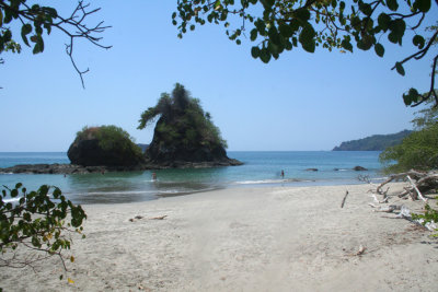 View of the Pacific Ocean and a rock with vegetation from Manuel Antonio beach.