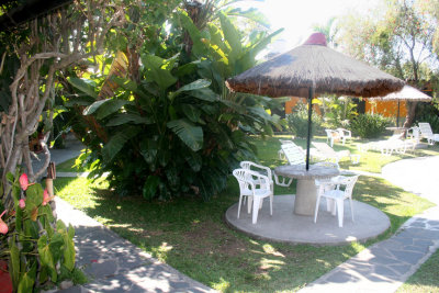 Umbrella, table and chairs with nice landscaping around the Hotel Cacique Inn.