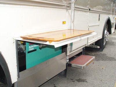 A REMOVABLE CUSTOM BOARD FOR FOOD PREPARATION AND GAS GRILL RESTS ON TOP OF THE ONAN QUIET DIESEL GENSET DOOR