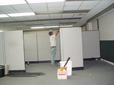 ONE OF THE FACTORY EMPLOYEES DISMANTLING A DIVIDER IN ONE OF THE OFFICES