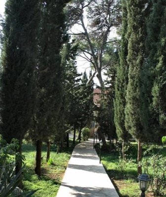 A Narrow Path Through A Green Yard Leads To The Church Structure.The Area Is Surrounded By High Wall.JPG