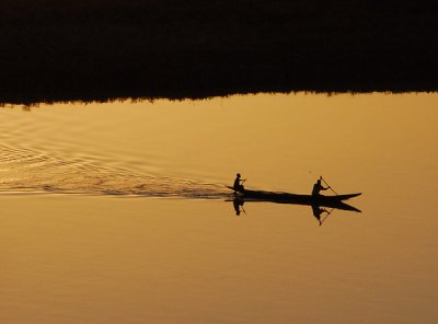Two men in a pirogue crossing the Niger at sunset, Niamey