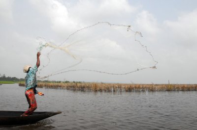 Fisherman casting a net for cadeau, Lac Nakou, Benin