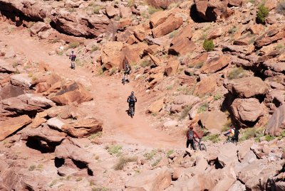 The riders at far right are walking their bikes through a rough portion of the road