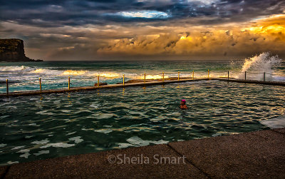 Swimmer in Avalon Rockpool with approaching storm