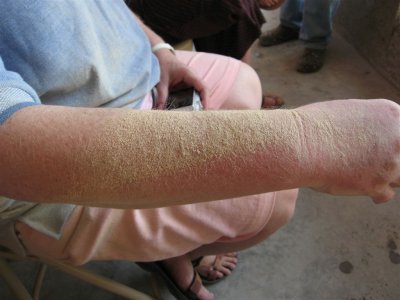 Jean's arm with sawdust from sanding the boards that will be pews