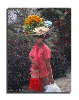 Woman carries tray on their head along the downhill road from Mt.Kyaiktiyo
