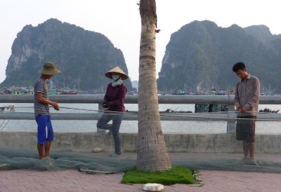 Mending fishing net on the sidewalk or by the seashore?