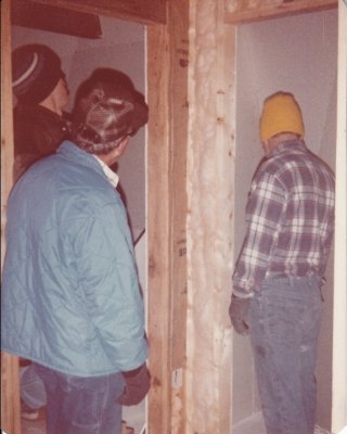Gerald and Dad in long sleeves, caps and gloves to install insulation, while Steve covers what they install with sheetrock. 