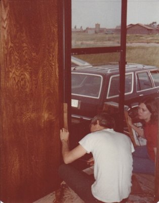Steve and Mary worked on installing the spring for the storm door. That's Mom and Dad's brown Ford station wagon in the background.