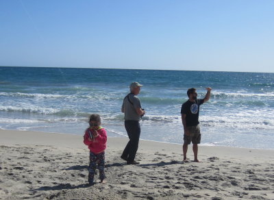 Devon lets out string while Grandpa and Dad look down the beach.