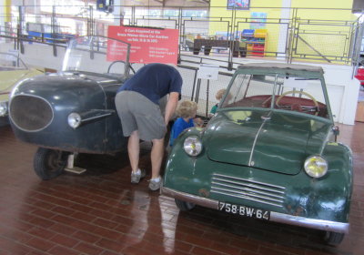Grandpa, Pierce and Max inspect a small car at the museum.