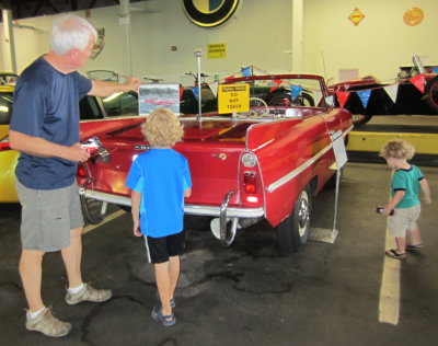 Grandpa shows Pierce a photo of the amphibious car moving in the water.