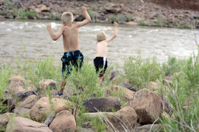 Boys rockhopping to river's edge