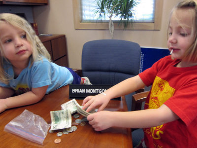 Kristina deposits the contents of her piggy bank.