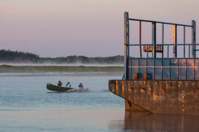 First canoe of the morning passes barges anchored at Moosonee.