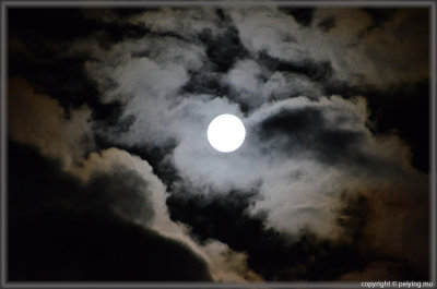The full moon playing peek-a-boo with the clouds