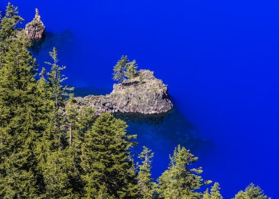 A rocky peninsula juts into the clear blue waters in Crater Lake National Park