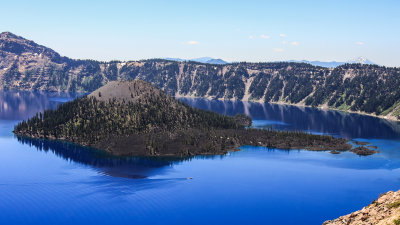 A boat glides past Wizard Island in Crater Lake National Park