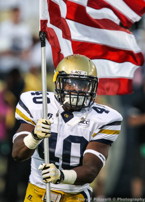 Georgia Tech LB Paul Davis carries the US Flag onto the field