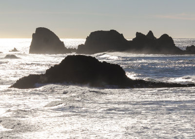A silhouette of rock formations in the surf as seen from above the beach at Ecola State Park