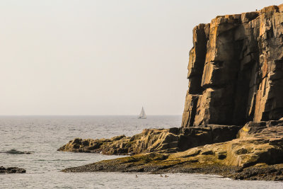 A sailboat passes Otter Point in the waters off of Acadia National Park