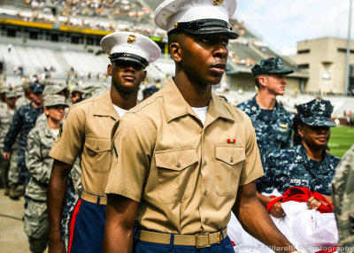 Members of the Armed Forces carry the flag onto the field