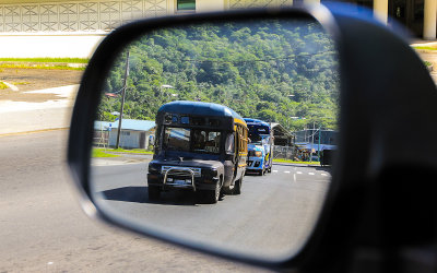 Aiga (family run) buses in the rear view mirror in American Samoa