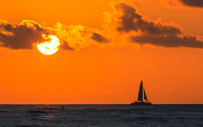 Catamaran and the setting sun as seen from Waikiki Beach