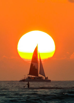 Catamaran silhouetted against the setting sun as seen from Waikiki Beach