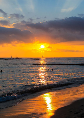 Rays of sunlight shoot upward at sunset on Waikiki Beach