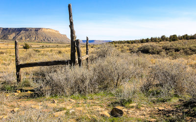 An old wooden fence with a pueblo wall at the base in Yucca House National Monument