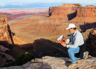 Reading Greg Blighs book Midlife Crisis on the Road on the edge of Shafer Canyon in Canyonlands National Park