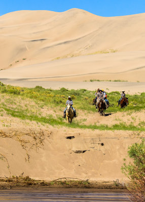 Visitors on horseback ride on the dunes near Medano Creek in Great Sand Dunes National Park