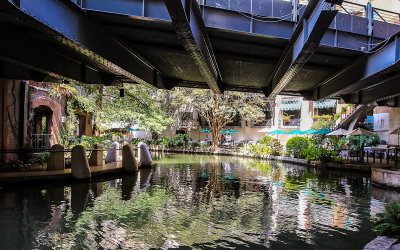 The San Antonio River runs under a bridge along the River Walk