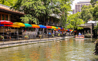 Restaurant umbrellas and a tourist boat along the San Antonio River Walk