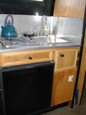 Kitchen - fridge, water heater, stove, sink, plus some storage, all on a wheelwell
