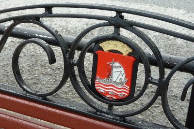 A rain-soaked bench with the city emblem