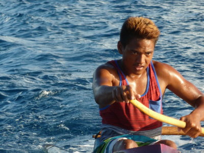 Guy in outrigger canoe getting a nice ride in the wake of our tender boat