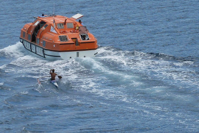 Outrigger canoe riding wake of tender boat