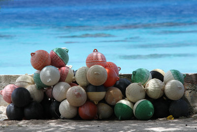 Pile of colorful buoys behind shop off road.