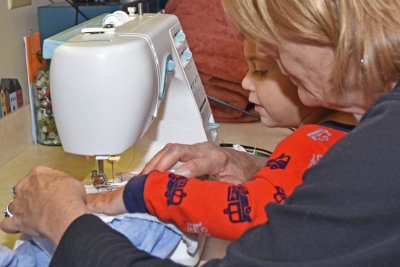 AJ helping Grandma sew the tags from his tattered blanket onto his new one