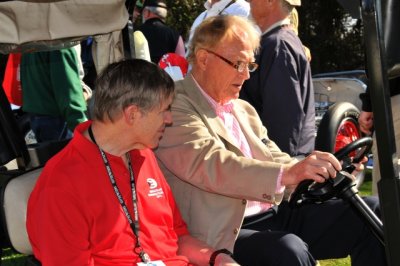 Racing legends Sam Posey, left, and Dan Gurney tour the show field on a golf cart (0423)