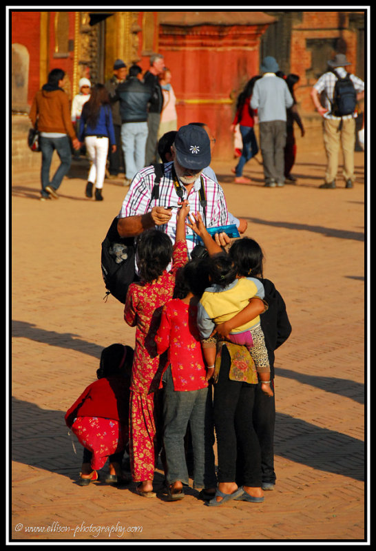 a tourist handing out pens to the children