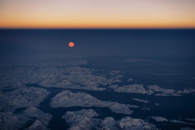 Moonrise over the icy and mountainous Eastern coast of Greenland