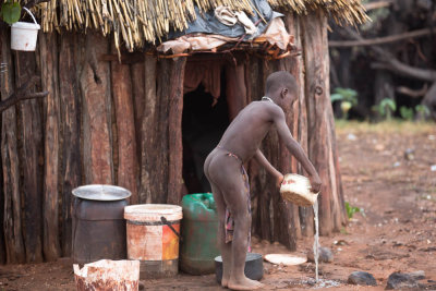 Himbajongetje bezig met huishoudelijke werkzaamheden